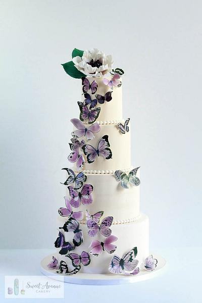 White wedding cake with purple butterflies cascade - Cake by Sweet Avenue Cakery