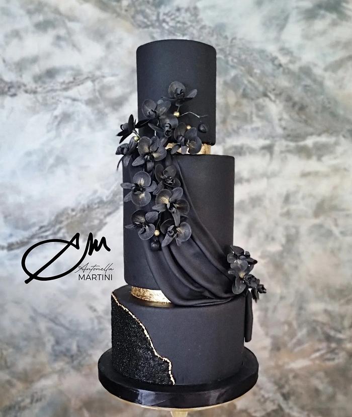A cake black and gold with orchid