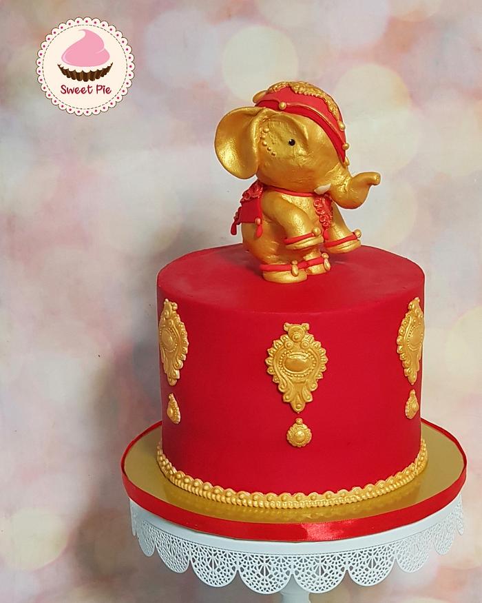 Gold and red cake with elephant topper
