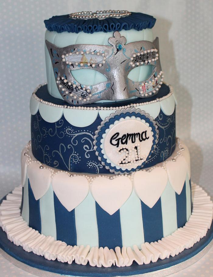 A Three Tier Masquerade ball cake topped with a handmade and handpainted Mask