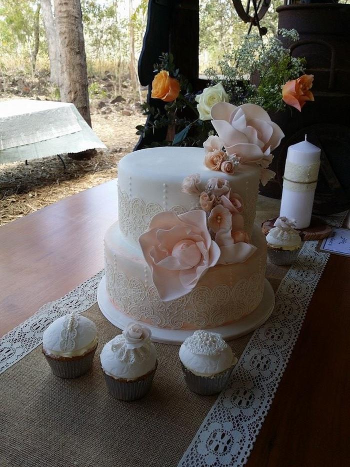 Wedding cake with lace and peachy pink large open roses.