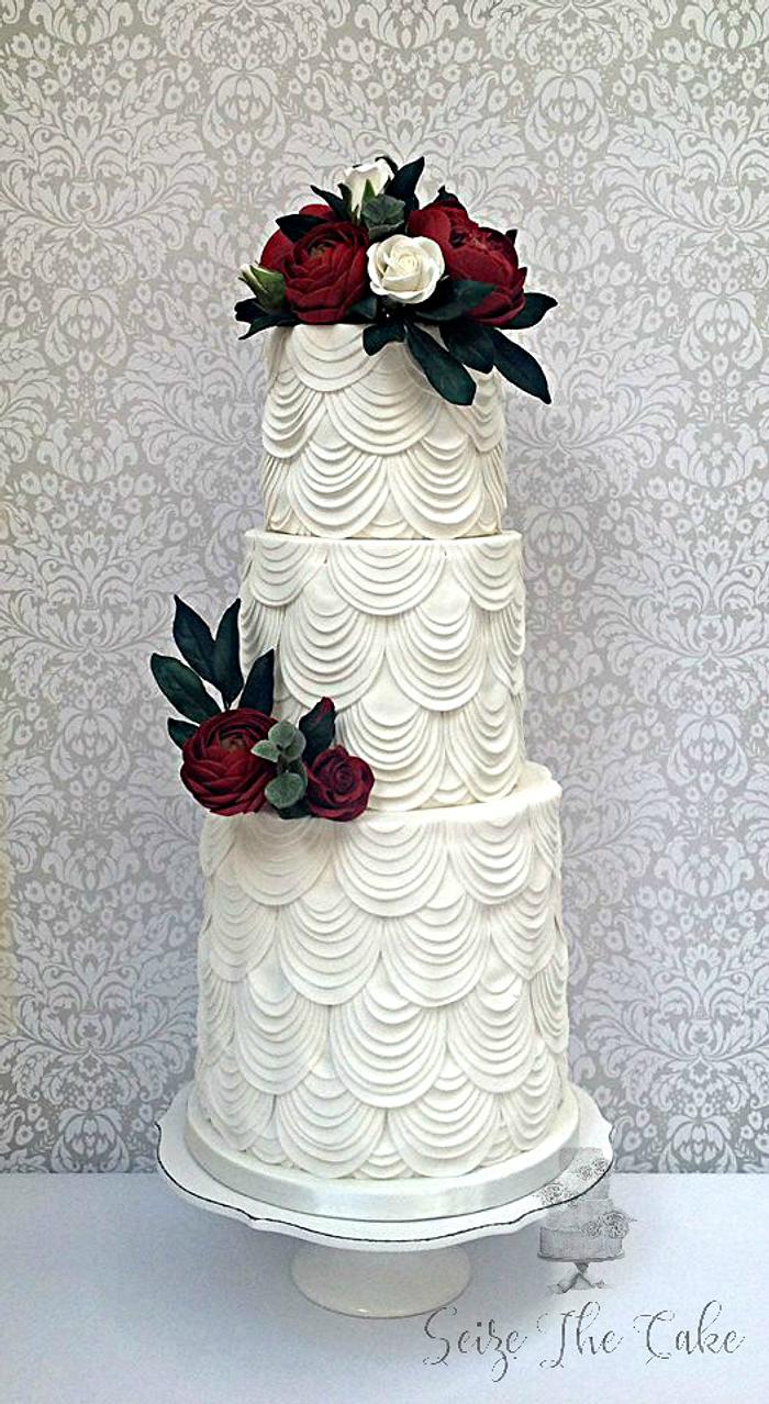 White drapes and red sugar flowers wedding cake