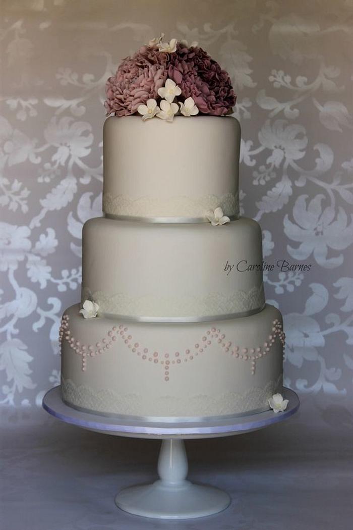 Wedding cake with purple ruffle flowers and beaded swags