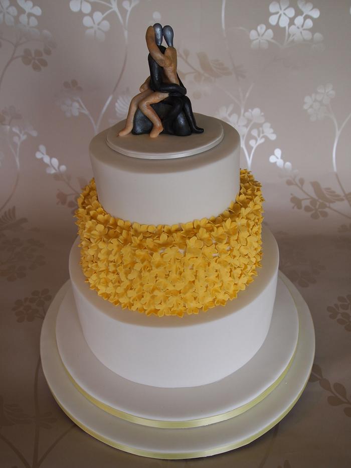 Wedding cake with yellow flowers and couple sculpture