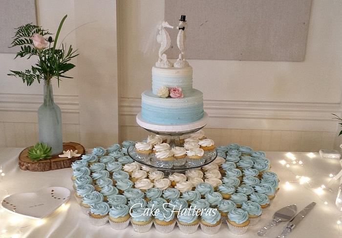 A cutting cake and cupcakes for a beach Wedding