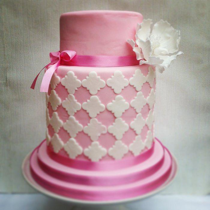 Pink double barrel cake with white quatrefoil design and sugar peony