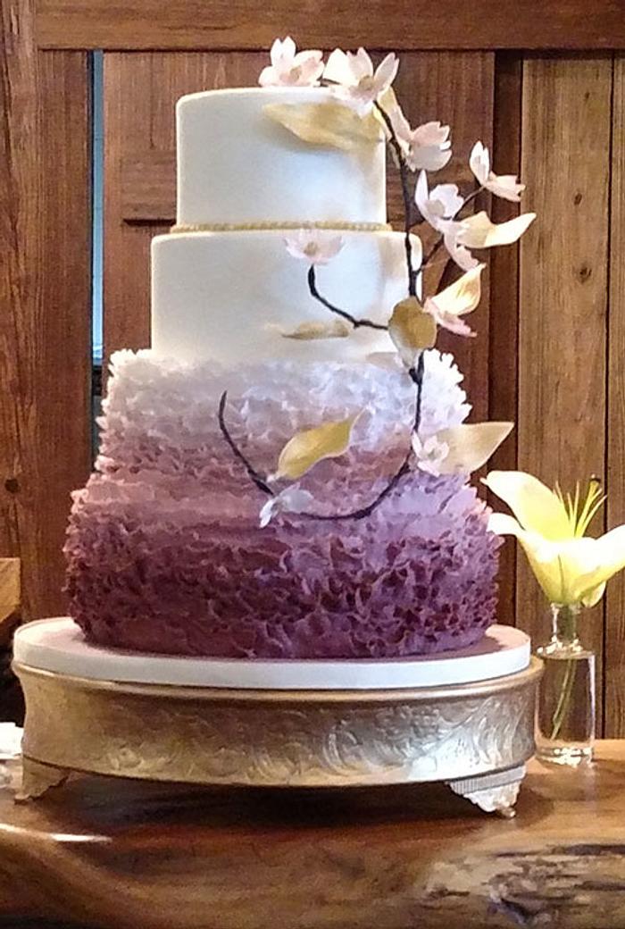 An ombre of frills and gold Dogwood flowers for this wedding cake. 