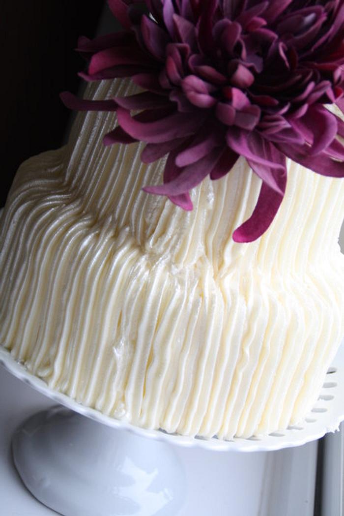 Butter iced two tier with purple flower