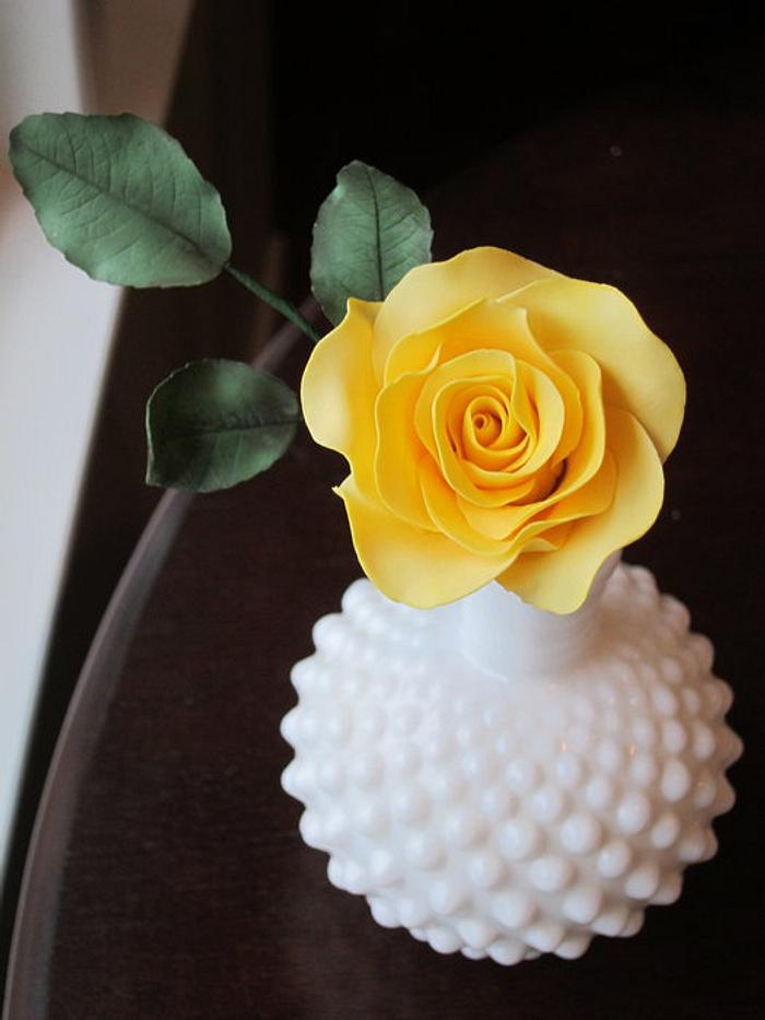 Yellow sugar rose and leaves in milk glass