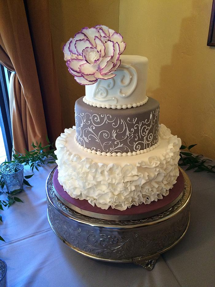A wedding cake with purple and grey. 