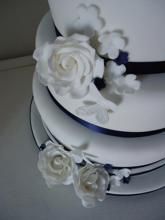Navy & white wedding cake with roses, blossom & butterfly details