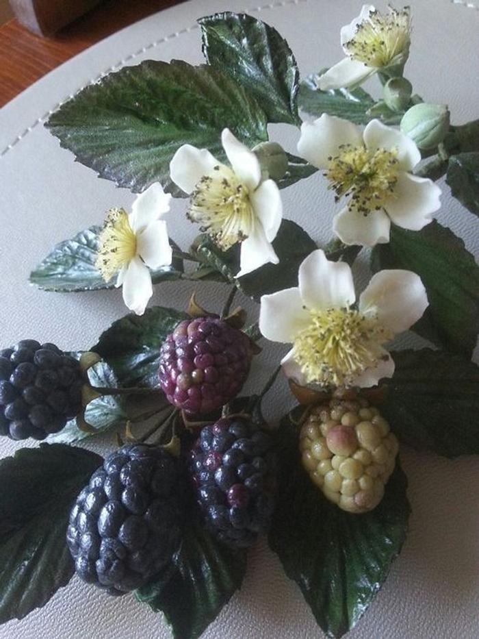 Arrangement of blackberries and flowers made from sugar.