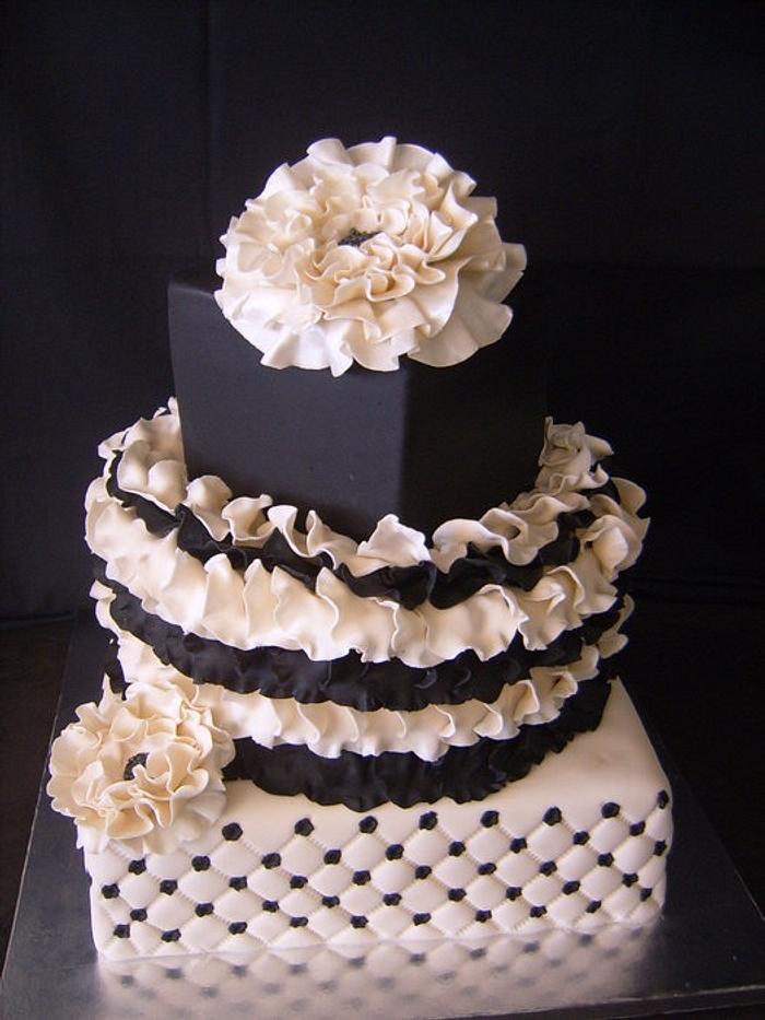 3 Tier black and cream cake with rose petals, flowers and quilting.