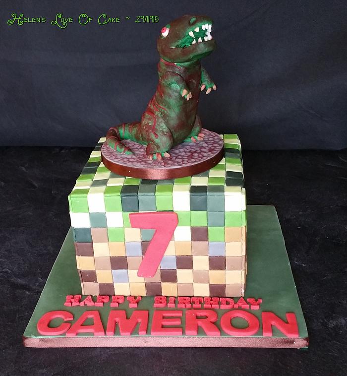 Mine craft cake with a dinosaur on top.