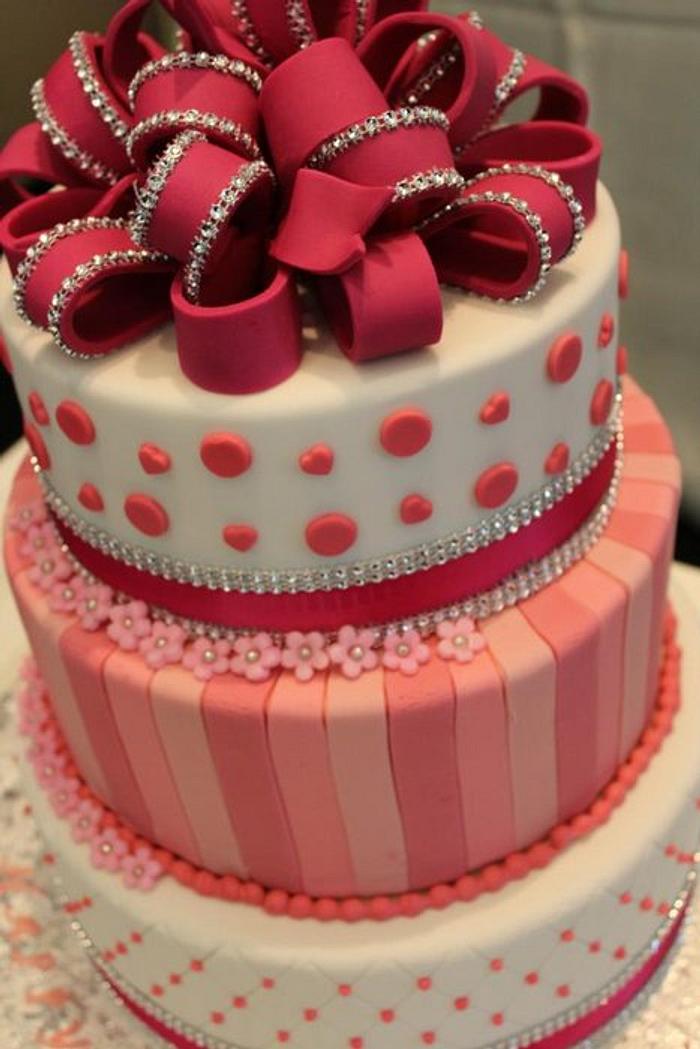 A pink birthday cake with big bow on top