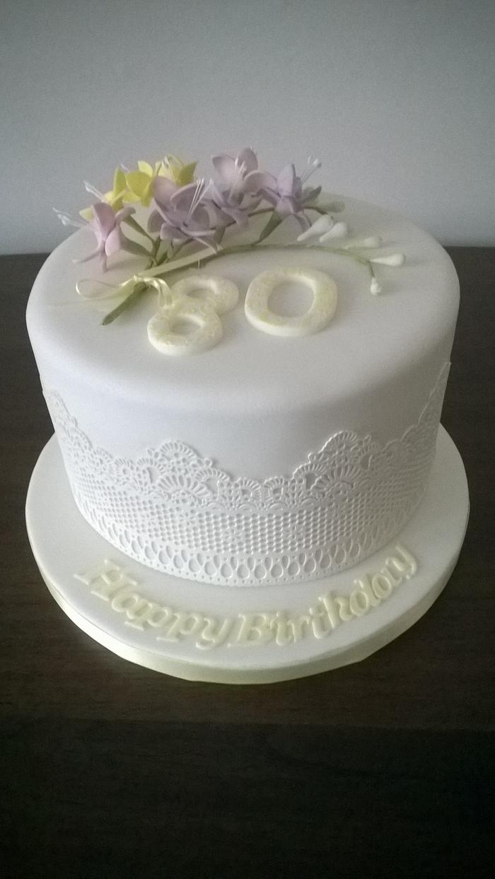 80th birthday cake with spray of freesias and edible lace