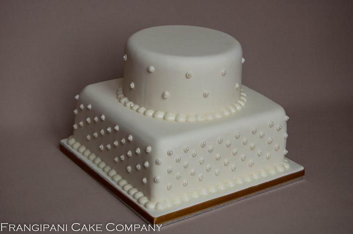 Two tiered ivory wedding cake with pearls