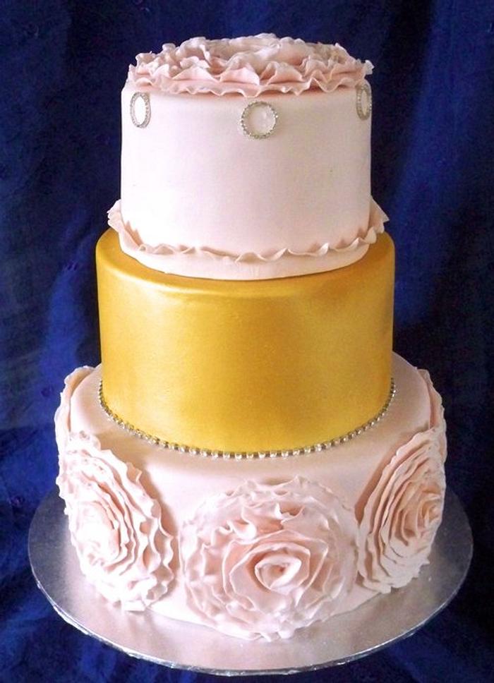 pink and gold wedding cake with large frill flower