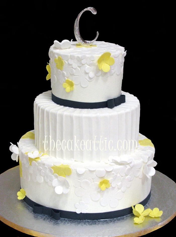 White and yellow flowers with pleated center tier wedding cake