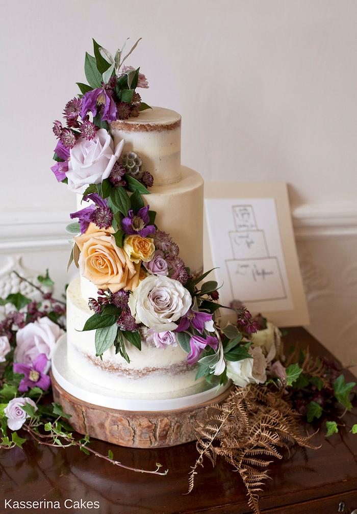 Semi-naked wedding cake with purple and amber fresh flowers