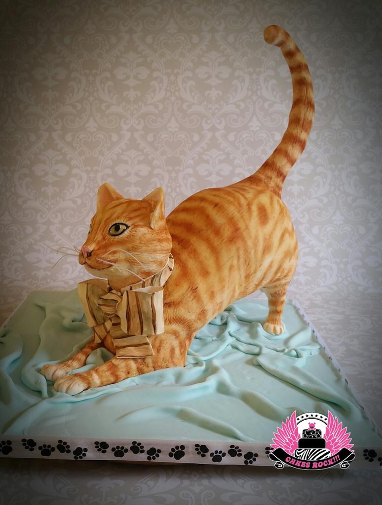 Black Orange Tabby Cat Sitting at Table Near Birthday Cake, with Candles  and Flowers