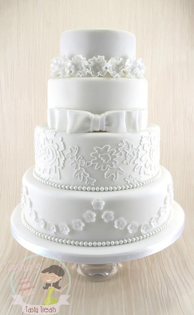 Photo of Gold and white 4 tier wedding cake with monogram topper