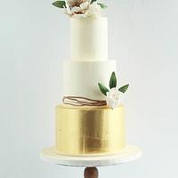 White and gold wedding cake with gold foil and flowers