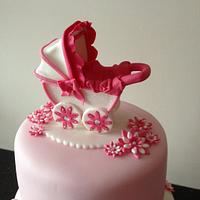 pink christening cake with pram topper