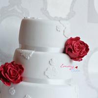 White wedding cake with lace motifs and big roses