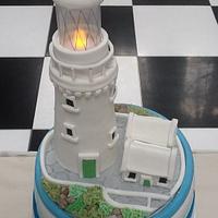 Nautical themed wedding cake with lighthouse topper