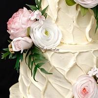 Cream wedding cake with pink and white ranunculuses and wooden topper