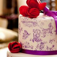 Purple toile stenciled cake with red tulips topper