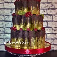 Wedding cake with berries and chocolate pencils.