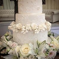White and gold lace cake with floating hydrangea blossoms 
