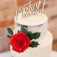 Semi-naked wedding cake with red sugarpaste roses and holly