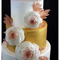 golden wedding display cake with ranunculuses