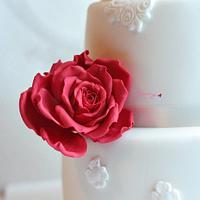 White wedding cake with lace motifs and big roses