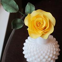 Yellow sugar rose and leaves in milk glass