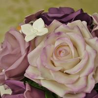 Purple and orange Cascading hydrangea and blossom wedding cake with a rose topper