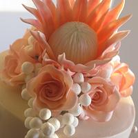 Three tier wedding cake with Protea and rose flower topper