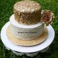 A simple vintage cake with gold lace work and sugar pearls .