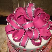 A pink birthday cake with big bow on top
