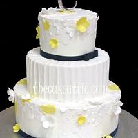 White and yellow flowers with pleated center tier wedding cake