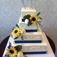 Wedding Cake with sunflowers, white roses and blue accents.